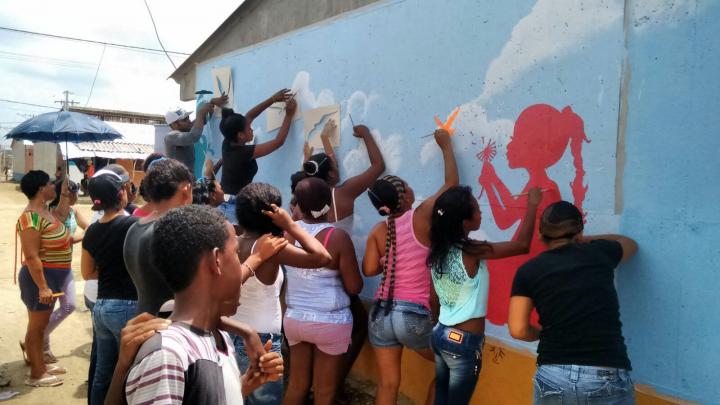 Women and children in Colombia come together to paint murals, with our partners LIMPAL