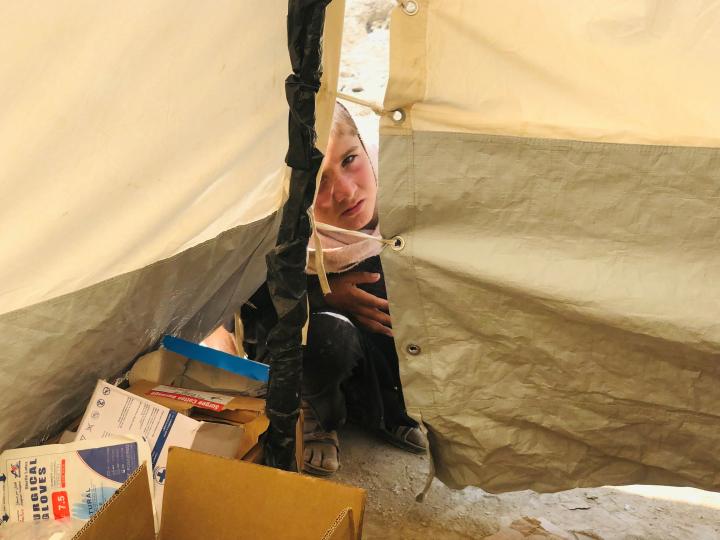 A boy looks into a tent to watch HealthNet TPO staff treat his father in Mohammadi village, Khost Province. Photo: UNHCR/Mohammad Haroon