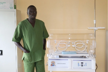 Dr. Alier, Maternal, Neonatal and Child Health Supervisor, stands next to the newly installed infant incubator in Terekeka Primary Health Care Centre.